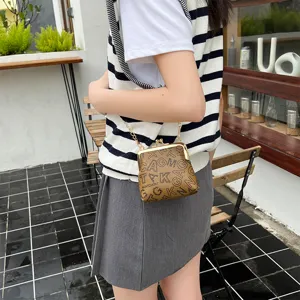 Detailed view of fashionable vintage kiss-lock cross-body bag with stylish letter print.