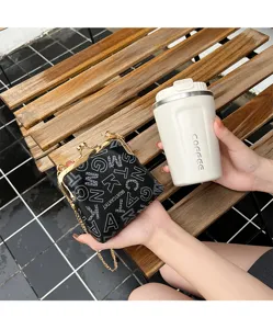 Details of black letter print kiss lock clasp bag with gold chain strap and metal frame.