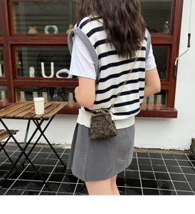 Women vintage kiss-lock cross body bag detail, chic chain shoulder bag with classic monogram pattern.