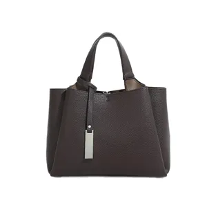 Classic brown leather tote bag with double handles and metal charm for women daily use.