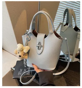 Light blue leather bucket bag with cute bear pendant, chic crossbody bag for women.