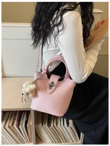 Stylish women's pink bucket bag detail, premium textured leather, commuter crossbody design.