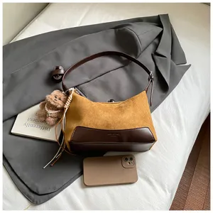 Close-up detail of vintage suede leather shoulder bag featuring cute plush bear charm and strap.