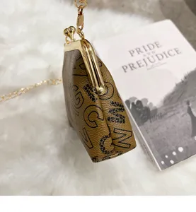 Detailed close-up view of the luxury brown monogram kiss-lock mini crossbody bag with gold chain.