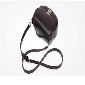 Detail view of dark brown leather saddle bag with gold metal lock closure and strap.
