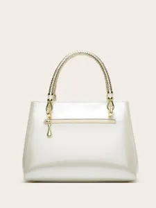 White patent leather handbag detail featuring a golden braided handle and metal hardware.