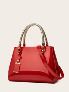 Red patent leather handbag detail view, featuring metallic woven handle and elegant design.