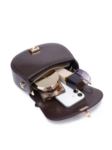 Brown leather saddle bag showing interior capacity with daily essentials like phone and makeup.