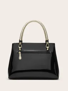 Details of black patent leather handbag featuring a stylish gold braided top handle hardware.