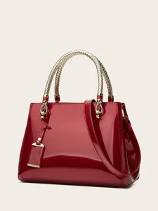 Detailed view of red patent leather handbag featuring luxurious gold woven handle and hardware.
