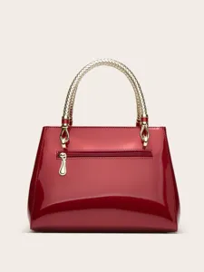 Close-up view of the red patent leather handbag featuring elegant gold woven handle and hardware.