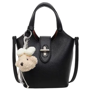 Elegant black leather bucket bag for women with chic metal lock and cute bear charm pendant.