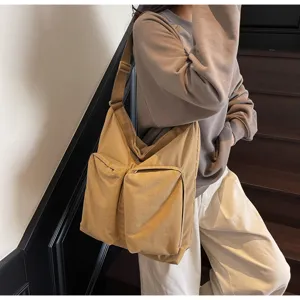 Khaki canvas messenger bag detail showing dual front pockets and adjustable shoulder strap.