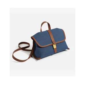 Detailed view of the stylish denim messenger bag with contrasting brown leather trim.