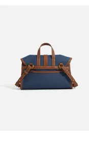 Denim messenger bag detail view, contrast brown leather trim, top handle and side straps.