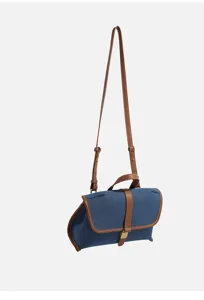 Denim crossbody bag detail showcasing contrast brown leather trim, flap buckle and sturdy strap.