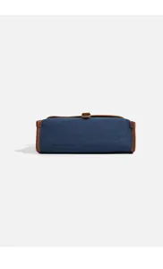 Detailed view of women's blue denim crossbody messenger bag with brown leather trim.