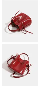 Red patent leather bucket bag with top handle and crossbody strap, stylish and compact design.