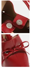 Red patent leather bucket bag metallic magnetic clasp and bow detail close-up view.