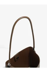 Leather bag handle detail close-up, showcasing premium brown texture and metal hardware.