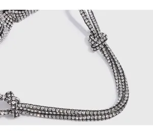 Close-up detail of luxury crystal rhinestone bag strap with glittering diamond knot design.