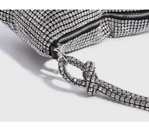 Sparkly rhinestone evening shoulder bag detail featuring a chic knotted strap and metal zipper.