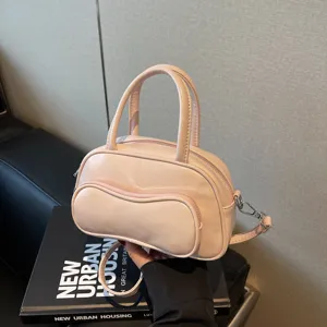 Chic pink leather pillow handbag with top handle and crossbody strap for daily fashion use.