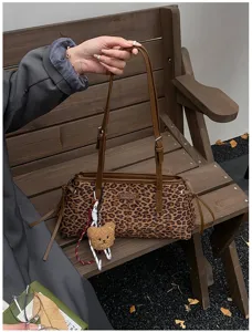 Leopard print shoulder bag for women, stylish underarm bag with cute bear pendant and strap.
