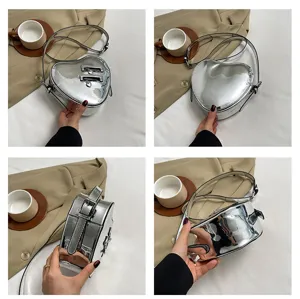 Détail de sac bandoulière cœur métallique argenté montrant la finition brillante et zips.