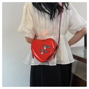 Vue détaillée du sac bandoulière rouge en cuir verni en forme de cœur avec fermetures.