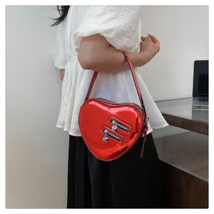 Détail de sac bandoulière cœur rouge brillant, curseurs de fermeture éclair cœur.