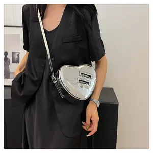 Détail de sac bandoulière argenté brillant en forme de cœur, style tendance et moderne.