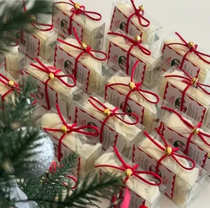 Scatole regalo di Natale trasparenti con eleganti nastri di velluto rosso e campanelli dorati.