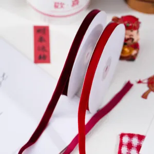 Red velvet ribbon detail shot, soft texture for DIY gift wrapping and holiday decoration.