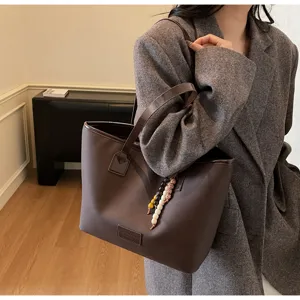 Detailed view of brown retro tote bag with bead charm, stylish commuter shoulder bag.