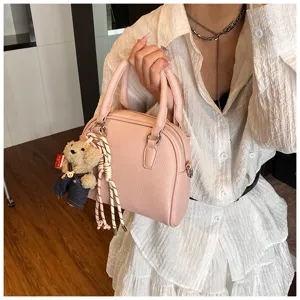 Detailed view of the pink lychee pattern shell handbag with cute bear charm and woven rope.