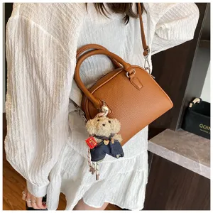 Brown leather shell crossbody bag with cute bear pendant, stylish casual handbag for women.