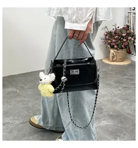 Black quilted shoulder bag detail featuring metal chain strap and cute bear charm pendant.