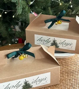 Christmas gift boxes with green ribbons and gold bells, perfect for holiday party wrapping.