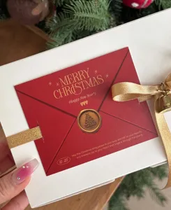Detailed close-up of Christmas gift wrapping ribbon, red card, and gold bell decoration.