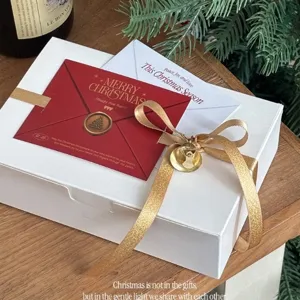 Christmas gift wrapping ribbon set with gold glitter bow, white box, and holiday cards.