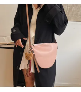 Detailed view of the stylish pink saddle bag worn by model, featuring cute bear pendant.