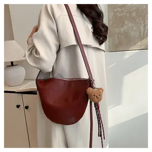 Wine red leather hobo shoulder bag detail featuring a cute plush bear charm accessory.