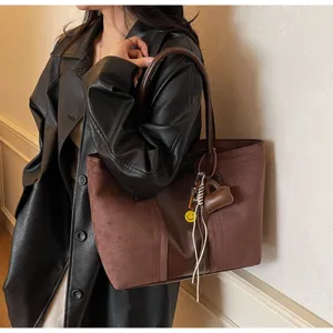 Vista dettagliata della grande borsa marrone in camoscio con ciondoli eleganti e tracolla.