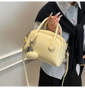 Detail view of the yellow vintage bowling handbag with metallic heart charm and handles.