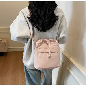 Vue détaillée d'un sac bandoulière rose à cordon porté au dos, accessoire élégant quotidien.