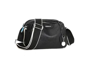 Detailed view of black leather soft women crossbody bag with wide strap and elegant metal hardware.