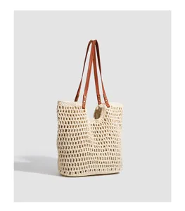 Beige crochet tote bag with brown leather handles, stylish straw beach bag for summer.