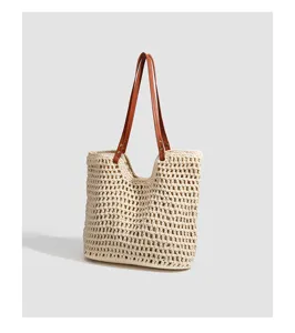 Close-up of the woven straw tote bag featuring contrast brown leather straps and detail.
