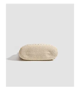 Detailed view of the bottom of a beige woven straw tote bag, showcasing neat texture.
